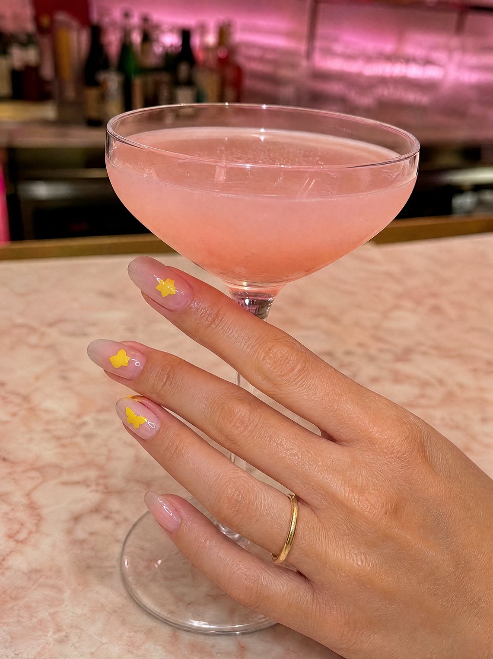 Yellow star, heart and butterfly stickers on her nails around a pink coupe