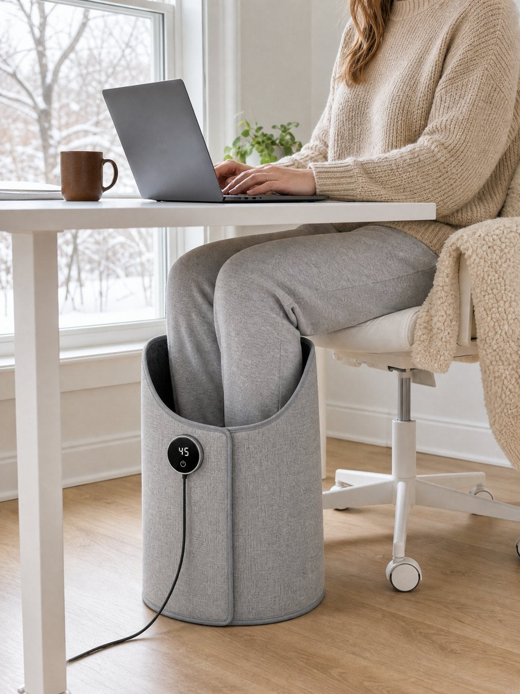 A woman works at her home desk with both legs inside the heater
